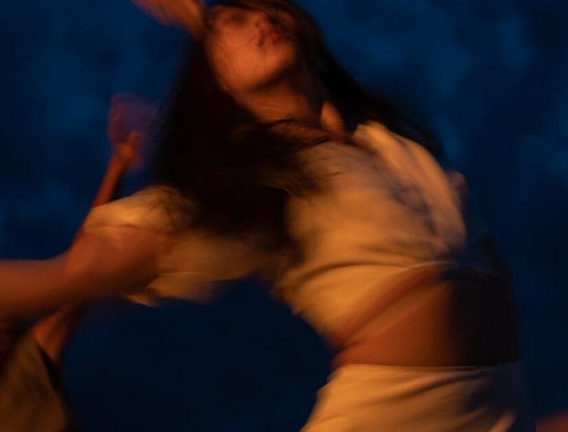 Blurred movement of women dancing joyfully during nighttime, creating an ecstatic and dreamy atmosphere.