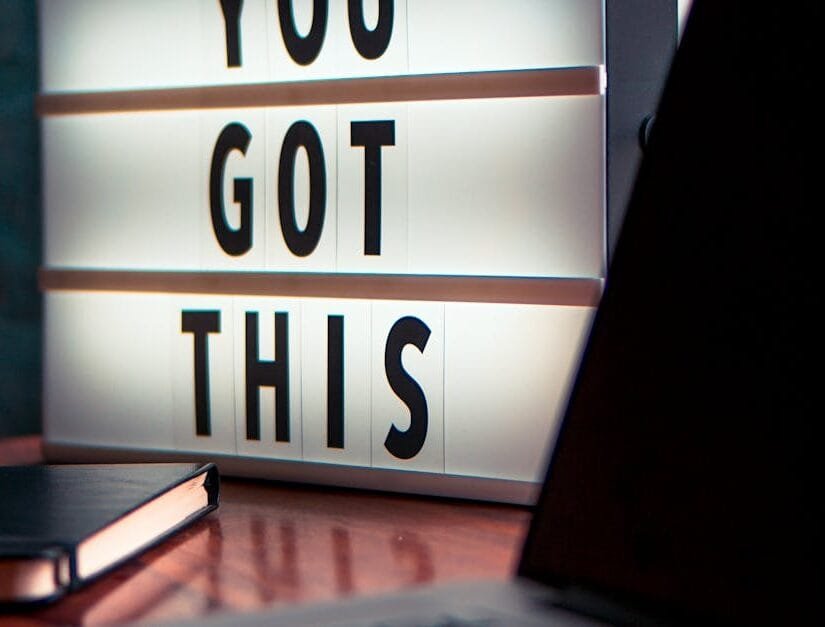 Illuminated lightbox with a motivational quote beside a laptop, promoting productivity.