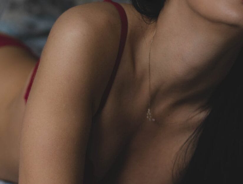 Close-up artistic shot of a woman in red lingerie with a necklace, capturing elegance and allure.